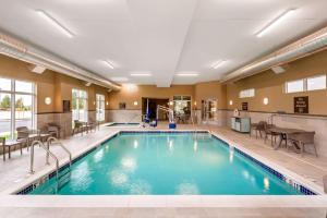 スポケーンにあるMainStay Suites Spokane Airportのホテル内のプール(椅子、テーブル付)