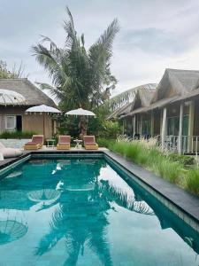 ein Pool mit Stühlen und Sonnenschirmen neben einem Haus in der Unterkunft Nusa Majesty in Nusa Penida