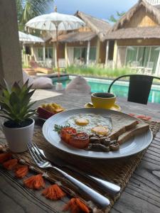 ein Frühstücksteller auf einem Holztisch mit einem Tisch in der Unterkunft Nusa Majesty in Nusa Penida