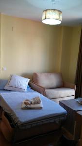 a room with two towels on a bed and a couch at Apartamentos Turísticos La Garza in Cáceres