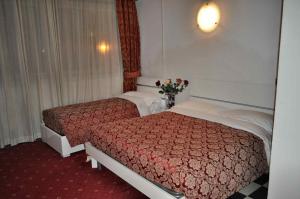 a hotel room with two beds and a vase of flowers at Hotel Giulietta e Romeo in Casal Palocco