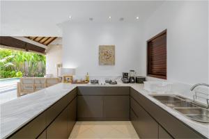 a kitchen with white countertops and a large window at Villa Nolan - Modern 3BR Private Villa with Pool in Padonan, Canggu in Kerobokan