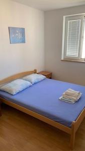 a bedroom with a bed with blue sheets and a window at Ratko Peris in Novalja