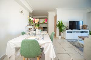 a dining room with a white table and green chairs at Proche Thalazur et plages, Parking privé, Piscine in Antibes