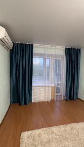 sala de estar con cortinas azules y ventana en Лободы 34 красиво и уютно, en Karagandá 3 fotos más