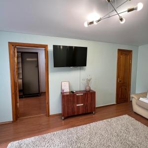 Una sala de estar con un televisor de pantalla plana en la pared. en Лободы 34 красиво и уютно, en Karagandá