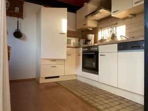 a kitchen with white cabinets and a tile floor at Ferienhäuser Fedderwardersiel Am Yachthafen 92 in Fedderwarderdeich
