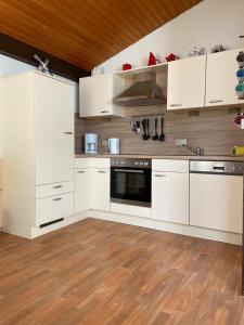 a kitchen with white cabinets and a wooden floor at Ferienhäuser Fedderwardersiel Am Yachthafen 93 in Fedderwarderdeich