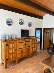 a living room with a wooden cabinet with a tv on it at Ferienhäuser Fedderwardersiel Am Yachthafen 93 in Fedderwarderdeich
