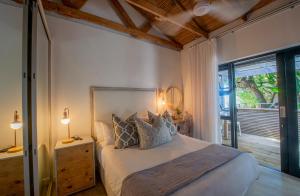 a bedroom with a bed with two lamps and a window at The Bungalow in Plettenberg Bay
