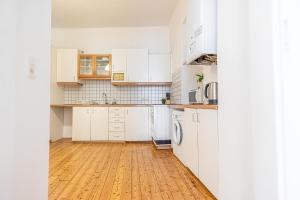 kuchnia z białymi szafkami i drewnianą podłogą w obiekcie Simple Apartment near Wiener Stadthalle w Wiedniu