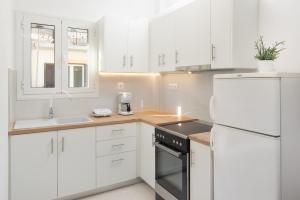 une cuisine avec des armoires blanches et un réfrigérateur blanc dans l'établissement Orfeas House Corfu, à Corfou