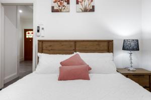 a bedroom with a white bed with two pink pillows at Stylish Home 5min drive to Sovereign Hill & Lake Wendouree in Wendouree