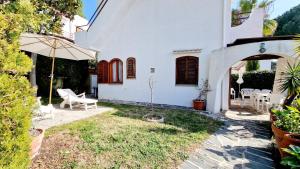 una casa blanca con un patio con sombrilla en Le Pleiadi - Casa Casoni, en Marcelli