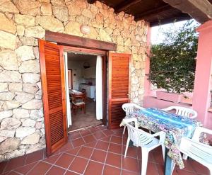 a patio with a table and chairs and a stone wall at Casa Lucca 3 in San Teodoro