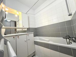 a bathroom with a tub and a sink and a mirror at Appartement Cosy à Belfort in Belfort