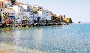 a group of white buildings on the shore of the water at Castel Abaso Boutique Apartments by Explore Andros in Andros