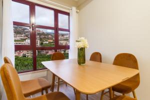 a table with chairs and a vase of flowers on it at GuestReady - Charming home in Câmara de Lobos in Câmara de Lobos +15 photos