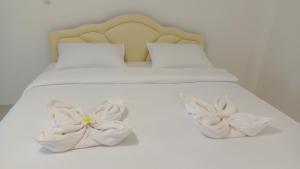 奈扬海滩Batikseafood Airport & Room的一张白色的床,上面有两朵白色的花