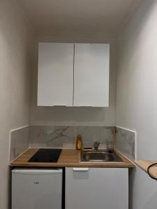 a kitchen with a sink and white cabinets at joli petit studio in Mantes-la-Jolie