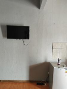 a flat screen tv on a wall with a refrigerator at Entire rental unit in Pretoria