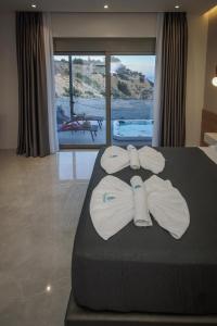 a hotel room with a bed with towels on it at Aquamarine Luxury Suites in Archangelos