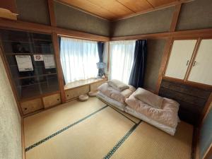 a living room with a couch in a room with windows at 古民家宿Tabi湊 in Hitachinaka