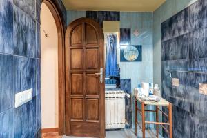 baño con puerta de madera y paredes de azulejos azules en Affittacamere Greenhause, en Florencia