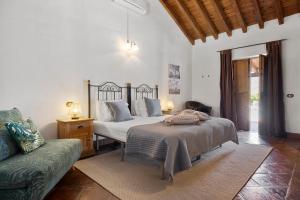 een slaapkamer met een bed en een bank bij Hacienda Riogordo in Ríogordo +59 foto's