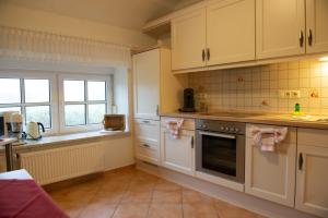 a kitchen with white cabinets and a stove top oven at Lütje Huus in Norden +10 photos