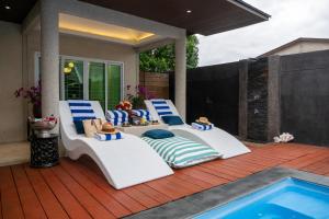 two lounge chairs on a deck next to a swimming pool at 2 bedrooms Amani Pool Villa Phuket in Thalang