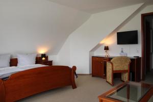 a bedroom with a bed and a desk with a television at Landhaus am Golfpark Inhaber Marko Nolden in Langenhagen