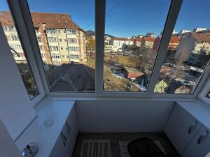a room with three windows and a view of a city at Magic Apartmens in Miercurea-Ciuc