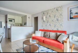 Una sala de estar con un sofá rojo y una cocina. en Appartement Moliets Plage Golf, en Moliets-et-Maa
