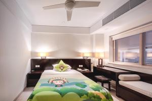 a bedroom with a bed and a desk and a window at Howard Johnson Resort Sanya Bay in Sanya