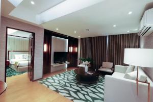 a living room with a couch and a bed in a room at The Harvest Hotel Managed by HII in Cabanatuan
