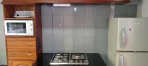 a kitchen with a stove and a microwave and a refrigerator at Maleh Plus in Kribi