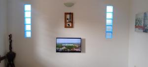 a tv mounted on a wall with three windows at Maleh Plus in Kribi +1 photo