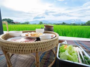 a table with a tray of food and a rice field at บ้านผ่อดอยกอยดาวพรีเมี่ยม in Ban Sop Nong