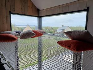 a room with a large window with pillows at Au bon coin de la baie in Vains