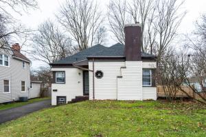 a white house with a chimney on top of a yard at Astonishing Home Mins Away Airport Dwtn UofR andRIT in Rochester