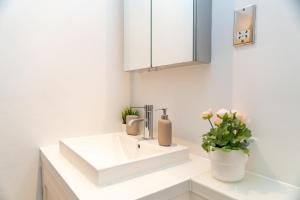 a bathroom with a white sink and a vase with flowers at Cuthbert Suite - Heart of Covent Garden! in London +44 photos