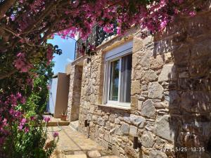 a stone house with flowers on the side of it at STONE of KAMARIZA in Áyios Konstandínos