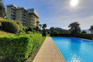 a swimming pool in front of a building at Tennis & Swim Apartment in Germignaga