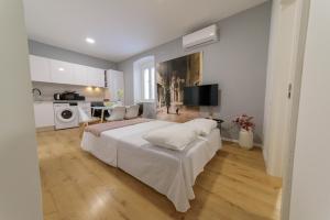 a bedroom with a large white bed and a kitchen at Apartman Poluotok 2 in Zadar