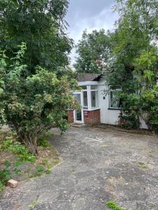 a white house with trees in front of it at 3 Bed Cottage Retreat - Private Garden & Parking in Orpington