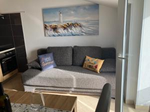 a living room with a gray couch and a lighthouse at Apartman Voch in Zambratija