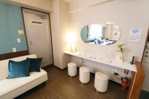 a bathroom with a couch and a sink with a mirror at Tommy Condominium Wakasa 201 in Naha