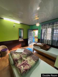 a bedroom with two beds and green walls at Odyssey Stays Yuksom in Pelling
