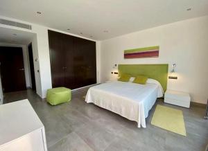 a bedroom with a white bed and a green headboard at Villa Lux Mar in Cala Llena +31 photos